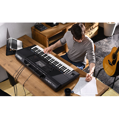 Photo of a person writing on sheet music while playing the Yamaha Arranger Workstation PSR-SX720