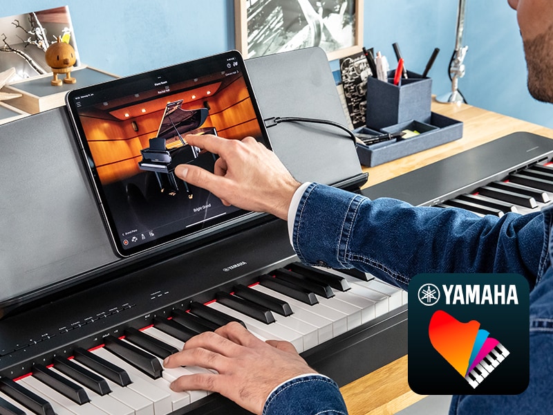 The Yamaha “Smart Pianist” app icon, together with a tablet placed on the m ature imageusic stand of the P-225