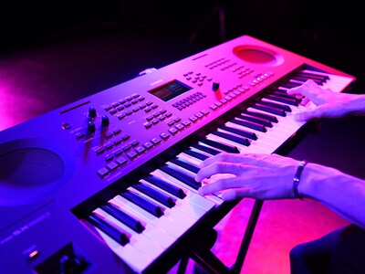 Nahaufnahme von Händen, die während eines Live-Auftritts auf einem Keyboard spielen.