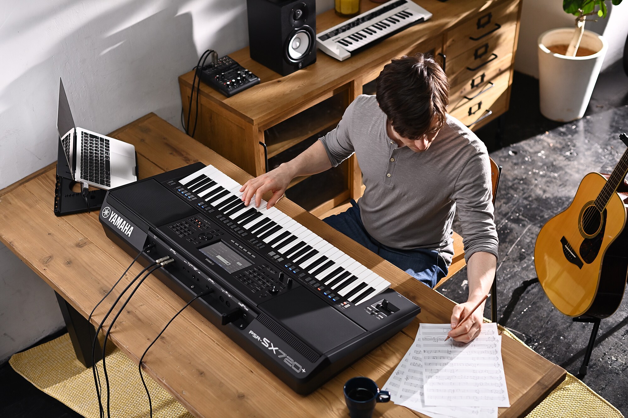 Foto einer Person, die Noten schreibt, während sie auf der Yamaha Arranger Workstation PSR-SX720+ spielt