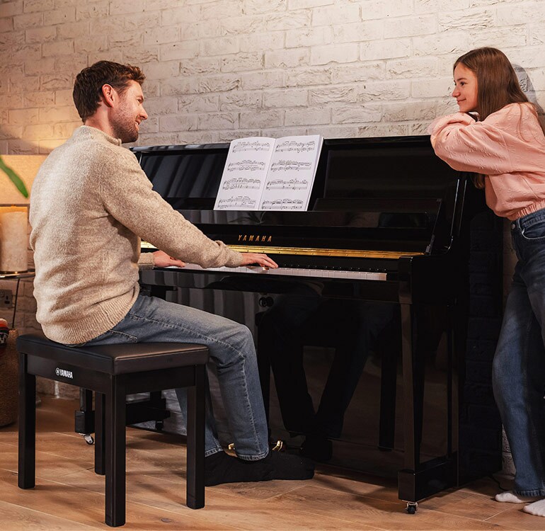 Eine Mutter und ihre Tochter spielen mit Freude auf einem Klavier der B-Serie