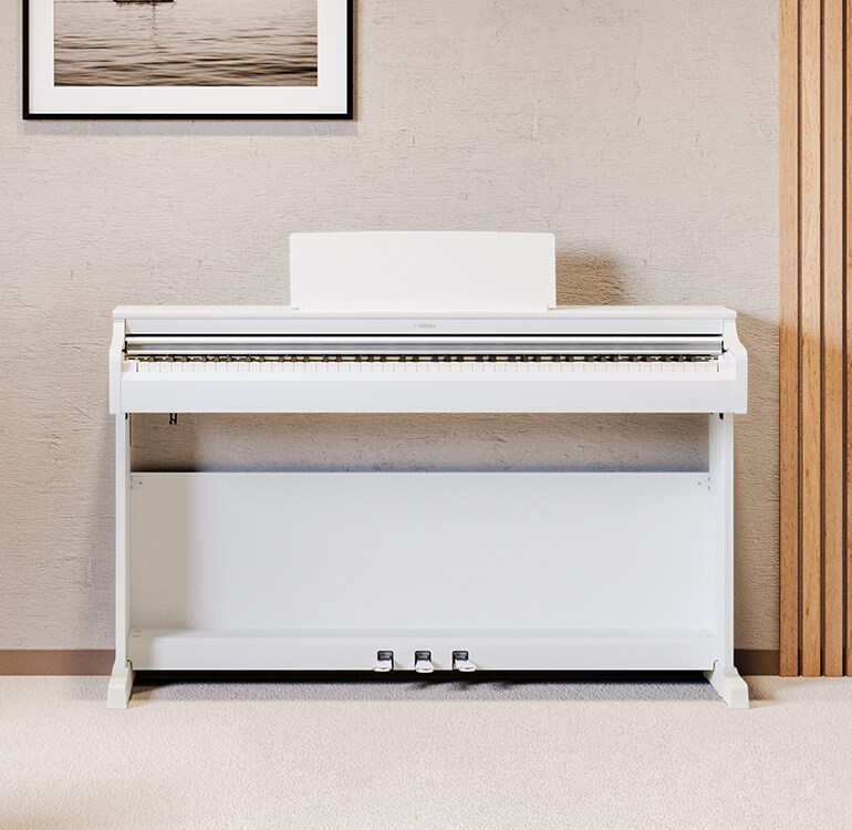 Ein Wohnzimmer mit einem weißen ARIUS Piano, Zimmerpflanzen und einem Sofa, harmonisch in die Einrichtung integriert