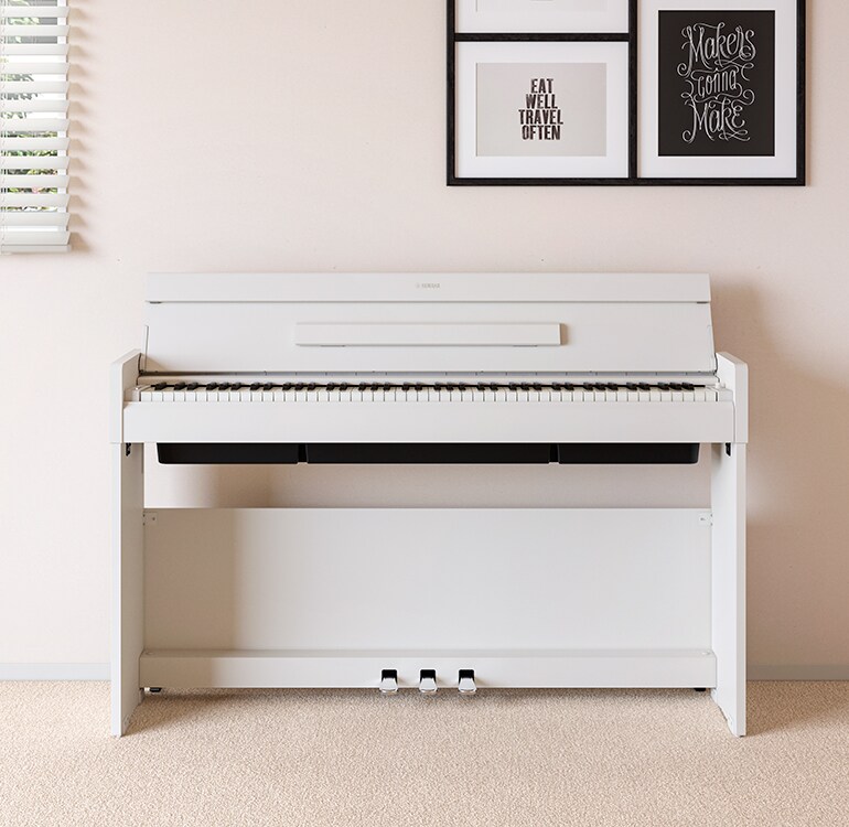 Ein Wohnzimmer mit einem weißen ARIUS Piano, das neben Wandregalen mit Lampen und einem Diffusor steht und harmonisch in die Einrichtung integriert ist.